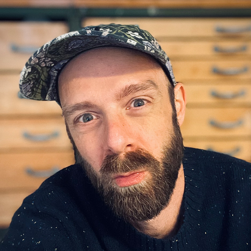Porträt mit Schirmmütze vor einem alten Schubladenschrank